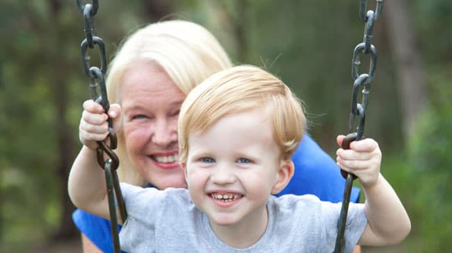 grandmother and child playing on swing and smiling